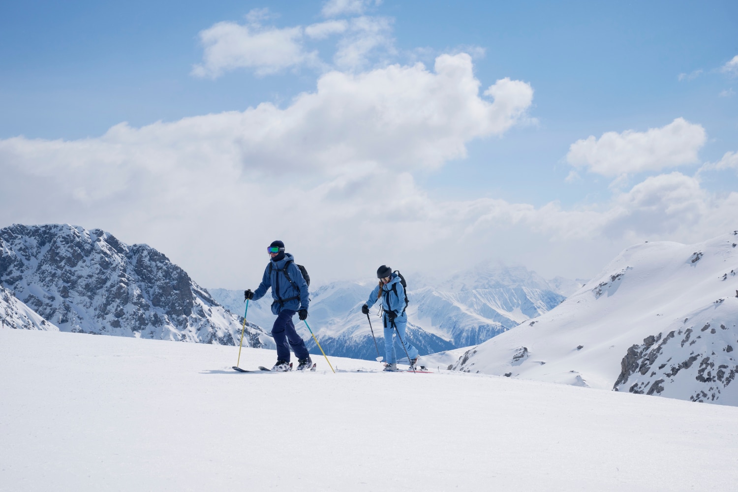 Two ski tourers on a snow-covered mountain slope.