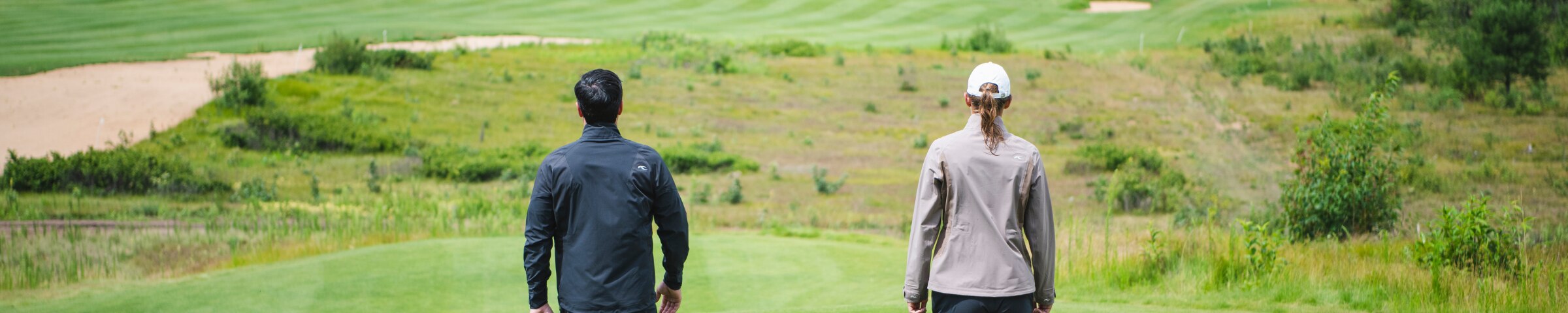 3 KJUS polos neatly folded on grass.