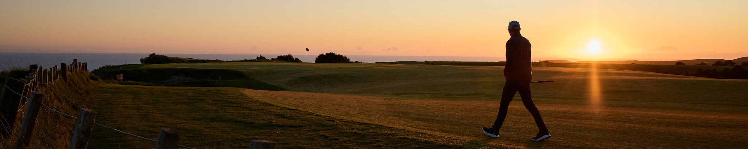KJUS golfer walking into the sunset on a golf course.