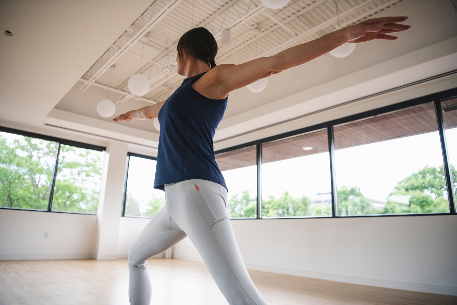 A woman in a blue-white KJUS outfit is doing yoga in a bright studio.